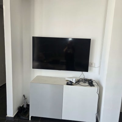 טלוויזיה מותקנת ותלויה על הקיר מעל שידה נמוכה