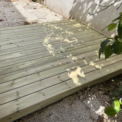 דק עץ מותקן בגינה עם צל עלים