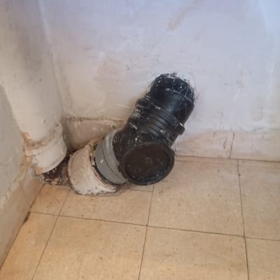 צינור ביוב מותקן בקיר עם אריחי רצפה