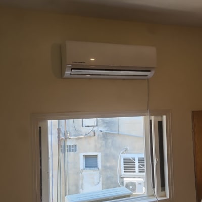 מזגן מותקן על קיר ליד חלון עם סולם