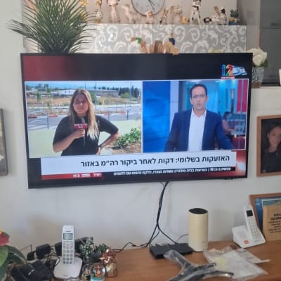 טלוויזיה מותקנת על קיר עם מדף וקישוטים