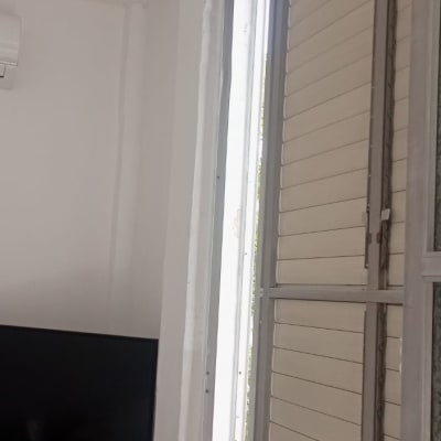 חלון עם תריסים פתוחים וקיר עם סימני שיפוץ