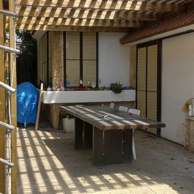 פרגולה מעץ עם טבעות תלייה וגינה קטנה