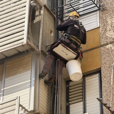 עבודת אינסטלציה בסנפלינג על חזית בניין מגורים