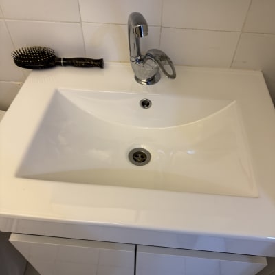 כיור לבן עם ברז מתכת מבריק ומברשת שיער