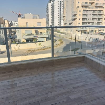 מרפסת עם רצפת עץ נקייה ומעקה זכוכית