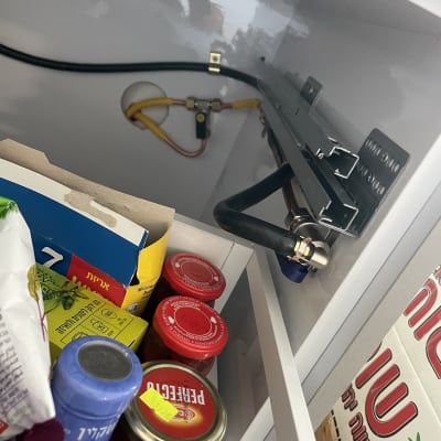 צינור גז ומחבר מתכת בתוך ארון מטבח