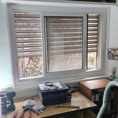 תריסים חומים פתוחים למחצה מעל חלון לבן