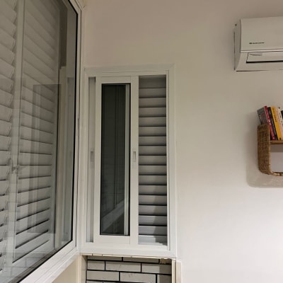 חלון עם תריסים ומזגן על קיר לבן