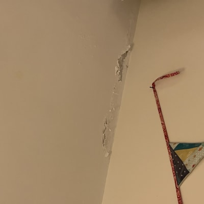 קיר עם קילופי צבע וסדקים בפינה