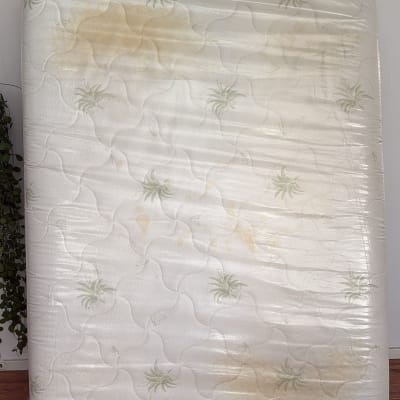 מזרן עם כתמים צהובים על רקע קיר לבן