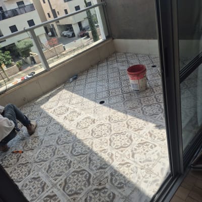 אדם עובד על רצפת מרפסת עם דלי וכלי עבודה