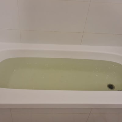 אמבטיה עם מים צהבהבים וברז מתכת