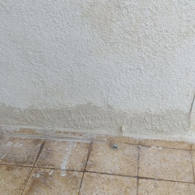 קיר צבוע עם סימני תיקון על הרצפה