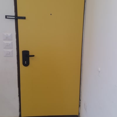 דלת צהובה עם ידית שחורה ורצפת אריחים מעוטרת