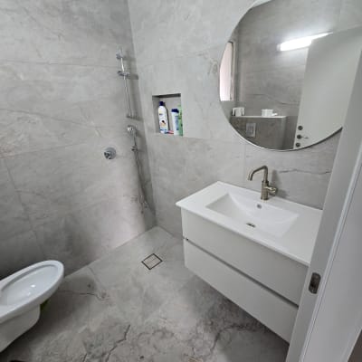 חדר אמבטיה עם אריחים חדשים, כיור ומקלחת