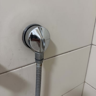 ברז כרום עם צינור גמיש על קיר אריחים