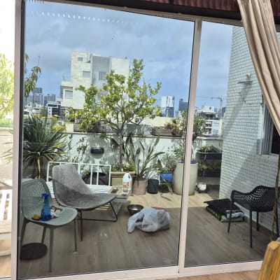 מרפסת עם צמחים וכיסאות, נוף עירוני ברקע