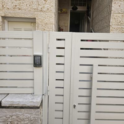 שער עם מקלדת כניסה ליד מבנה אבן