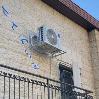 יחידת מיזוג אוויר מותקנת על קיר חיצוני עם דגלי ישראל