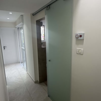 דלת הזזה מזכוכית חלבית המותקנת על מסילת אלומיניום עליונה