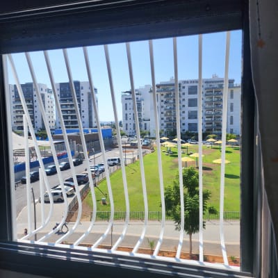 סורגים לבנים על חלון עם נוף עירוני