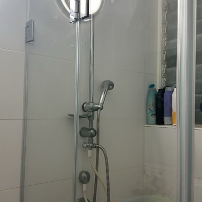 מקלחת עם ראש מקלחת עגול ובקבוקי שמפו