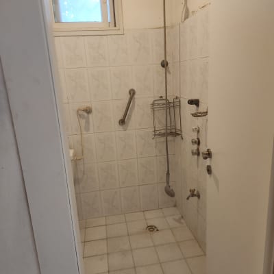 מקלחת עם אריחים לבנים, מוט אחיזה ומקלחון