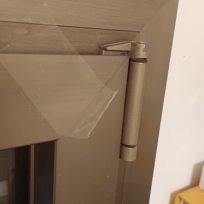 ציר מתכת על תריס חום עם סרט דבק שקוף