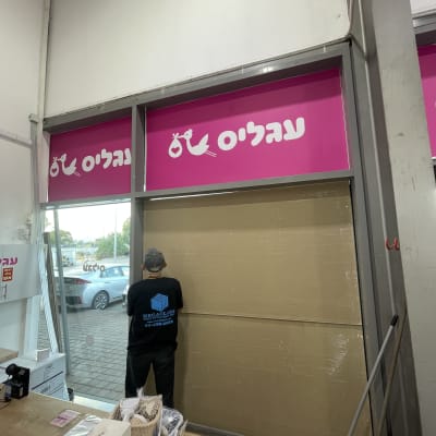 עובד מתקין זכוכית בחנות עם שלט מגה גלאס