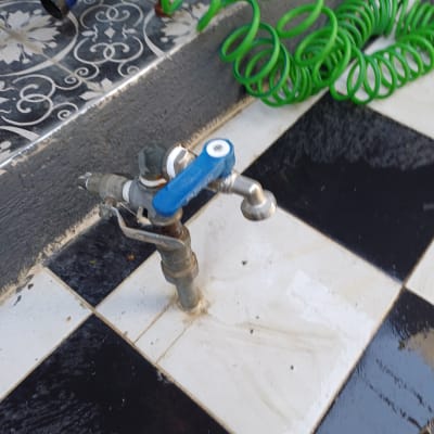 ברז מים עם צינור ירוק על רצפה שחור-לבן