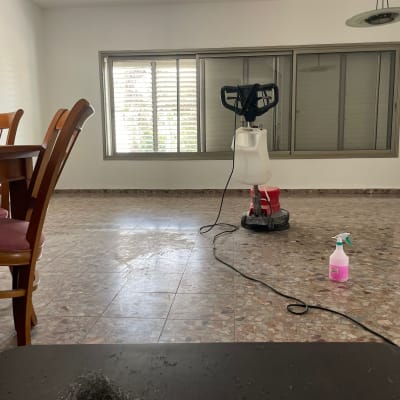 מכונת ניקוי רצפה ובקבוק חומר ניקוי בחדר ריק