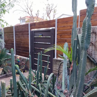 גדר עץ חומה עם שער מתכת בגינה