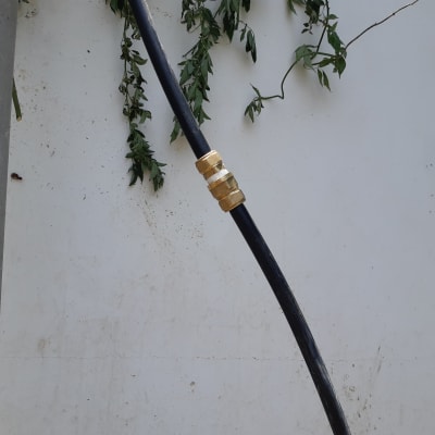 צינור שחור עם מחבר מתכת מוזהב על קיר לבן