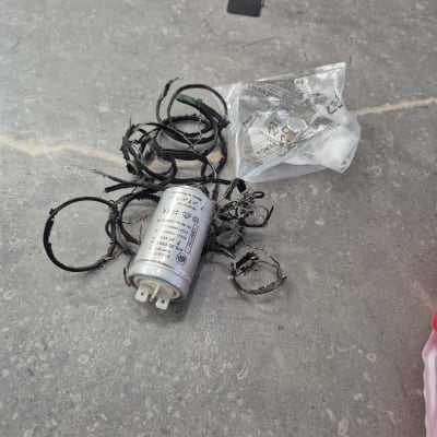 קבל חשמלי עם חוטים קרועים על רצפה אפורה