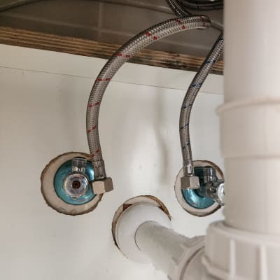 צינורות מתכת מחוברים לברזים מתחת לכיור