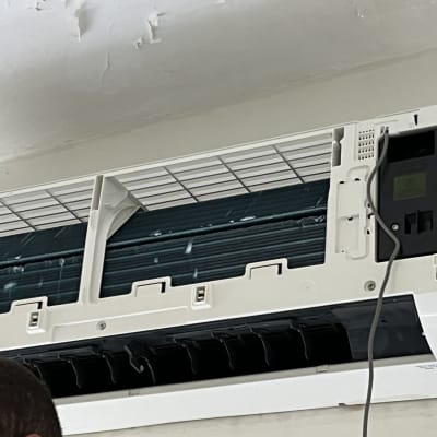 אדם עובד על מזגן מותקן על קיר