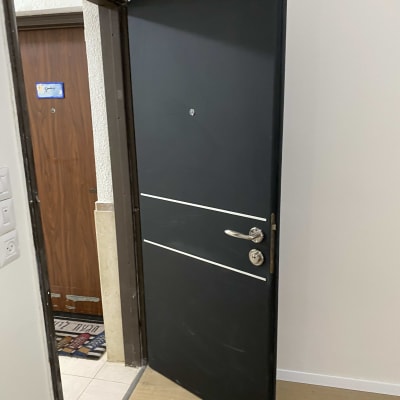 דלת שחורה עם ידית כסופה ופסים לבנים