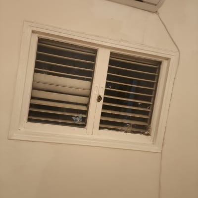 חלון עם תריסים ומזגן מותקן מעל