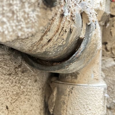 צינור מתכת עם חלודה ותיקון על קיר בטון