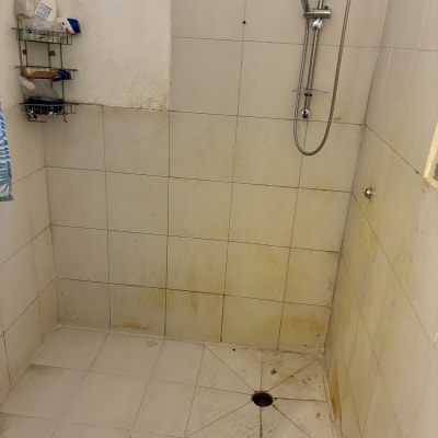 מקלחת עם אריחים מלוכלכים וראש מקלחת