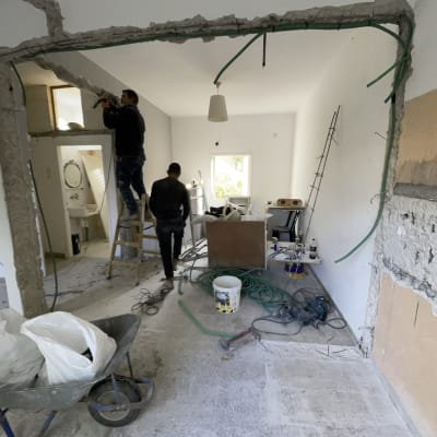 שני פועלים עובדים על שיפוץ קיר עם כלים וחוטי חשמל