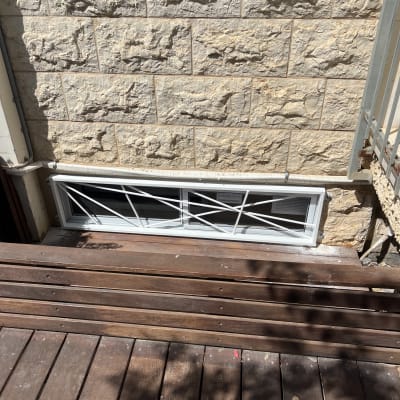 חלון עם סורגי אלומיניום על קיר אבן