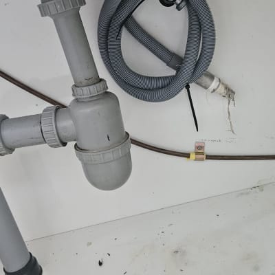 צינור פלסטיק אפור מתחת לכיור עם חיבורים