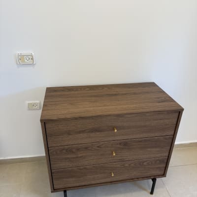 שידה מעץ עם שלוש מגירות ופטיש על הרצפה