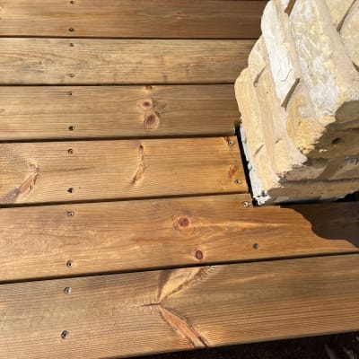 דק עץ עם עמוד אבן בפינה