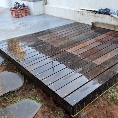 דק עץ מותקן בחצר עם אבנים מסביב