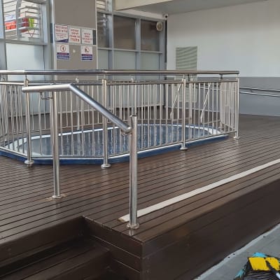 רצפת עץ עם מעקה מתכת סביב בריכה קטנה