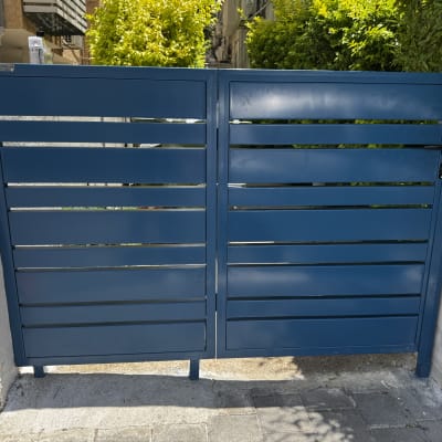 שער מתכת כחול עם צמחייה ברקע