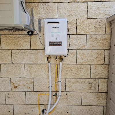 מחמם מים גז מותקן על קיר אבן עם צינורות